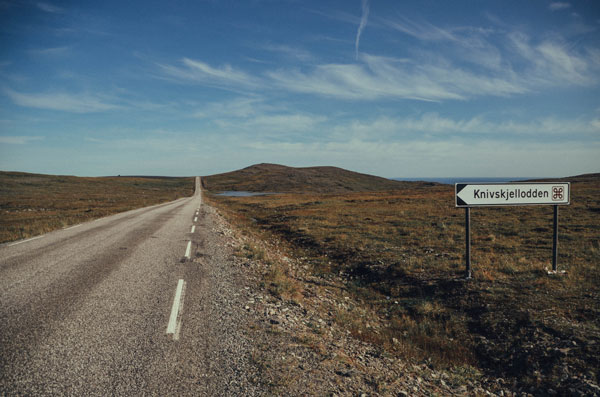 Foto von einer weitern Straße die durch eine grün-braune Umgebung in Skandinavien führt