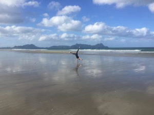 Person macht Handstand am Strand in Neuseeland